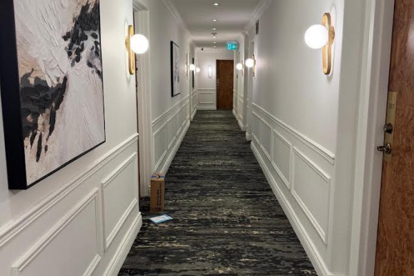 Long, carpeted apartment hallway with white paneled walls, wall sconces, and artwork. - 308 - 1901 Bayview Avenue, Toronto