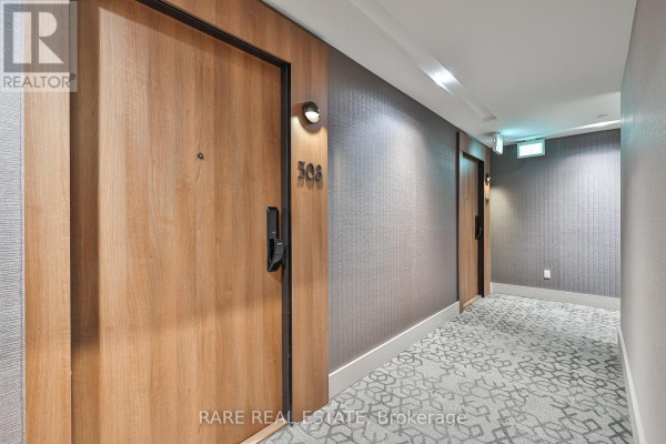 Apartment building hallway with wood doors and patterned carpet. - 308 - 21 Park Street E, Mississauga
