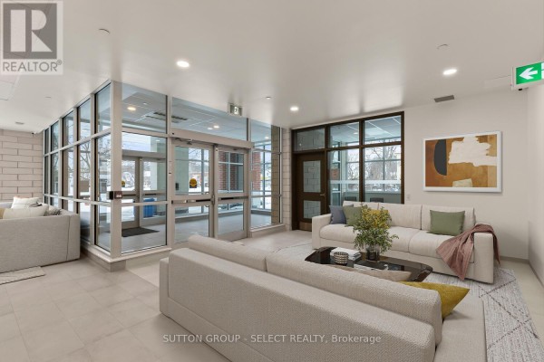 Building lobby with beige tiled floor, glass walls, and modern seating. - 308 - 351 Hill Street, London East