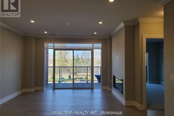 Living room with neutral paint, a fireplace, and sliding glass doors leading to a balcony. - 308 - 480 Callaway Road, London North