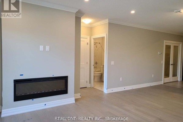 Interior view showing a neutral-colored living area with a contemporary fireplace and access to a bathroom. - 308 - 480 Callaway Road, London North