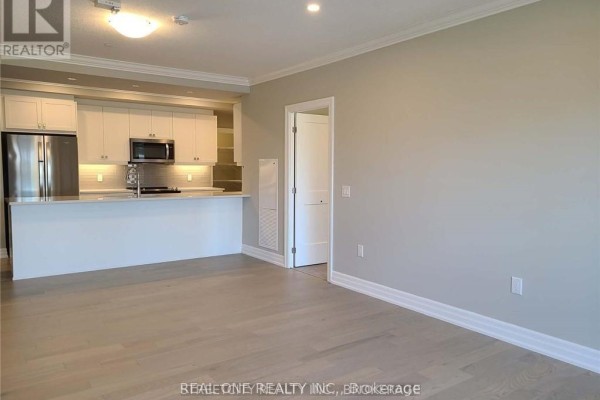 Open-concept living space featuring a modern kitchen with white cabinetry and stainless steel appliances. - 308 - 480 Callaway Road, London North