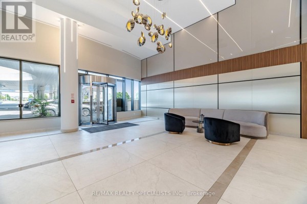 Elegant building lobby with light tile floors, modern seating, and decorative lighting. - 308 - 5105 Hurontario Street, Mississauga