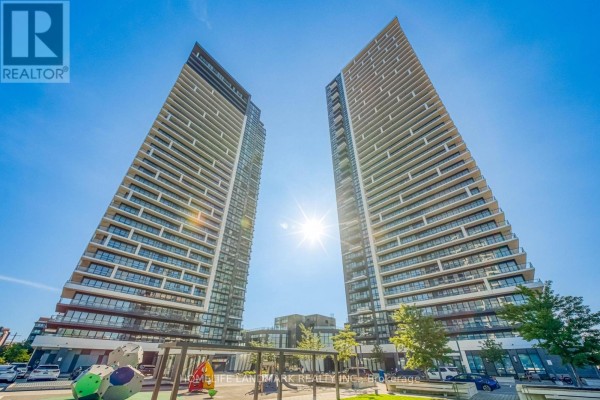 Living area with sectional sofa, mounted TV, and a large window overlooking the city. - 308 - 8 Water Walk Drive, Markham