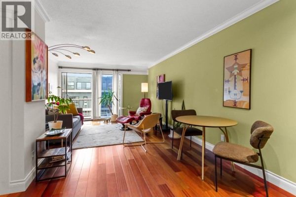 Living room with hardwood floors, a grey sofa, red armchair, and a dining table. - 308 2040 Cornwall Avenue, Vancouver