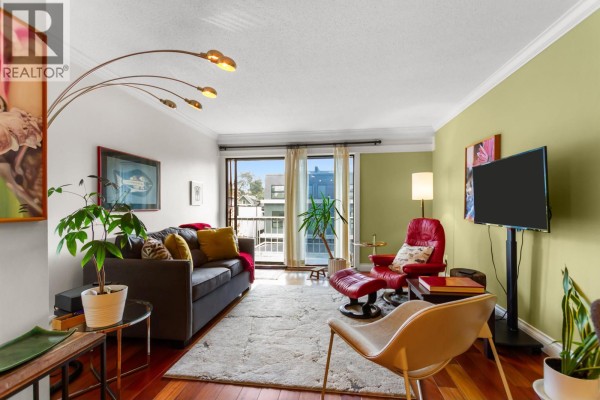 Living room furnished with a sofa, armchair, a floor lamp, and a television. - 308 2040 Cornwall Avenue, Vancouver