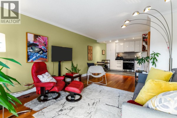 Living and dining area showing a sofa, armchair, television, and a small dining set. - 308 2040 Cornwall Avenue, Vancouver