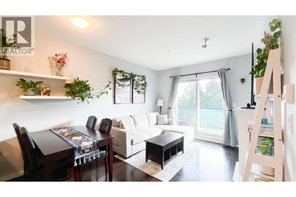 U-shaped kitchen with light wood cabinets, stainless steel appliances, and black countertops. - 308 22290 North Avenue, Maple Ridge