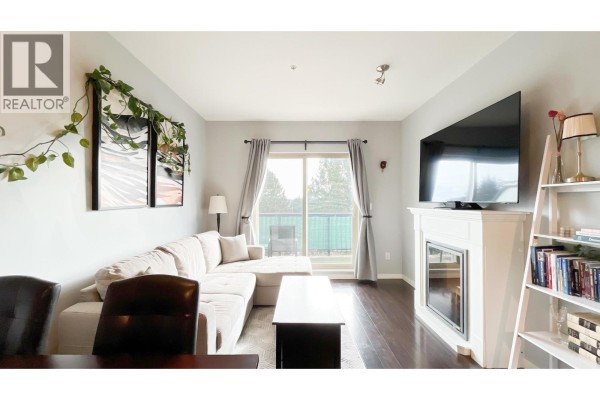 Living and dining area with sectional sofa, dining table, and sliding glass door. - 308 22290 North Avenue, Maple Ridge