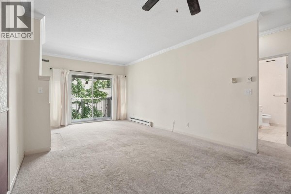 Living room with beige carpet, sliding glass door, and beige curtains. - 308 4728 53 Street, Delta
