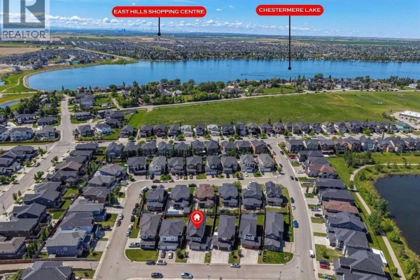 Aerial view of a residential neighborhood with Chestermere Lake and East Hills Shopping Centre in the distance. - 308 Kinniburgh Link, Chestermere