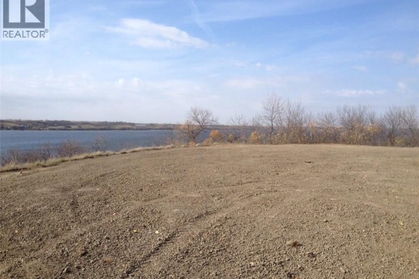Open land with a view of the lake and sparse trees in the background. - 308 Mckillop Road, Last Mountain Lake