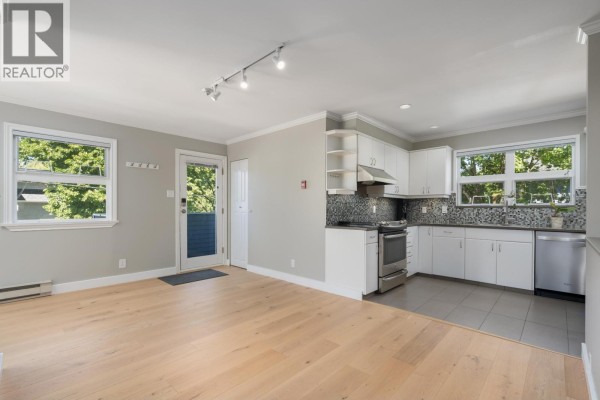 Open concept living and kitchen area with light wood floors and white cabinets. - 3085 Maple Street, Vancouver