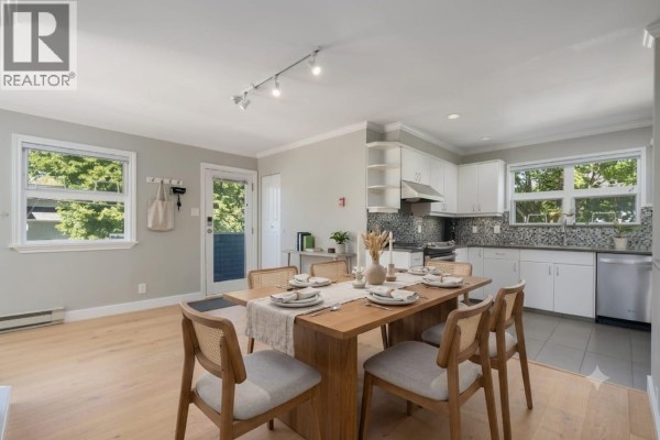 Dining area with a wooden table, chairs, and adjacent open kitchen space. - 3085 Maple Street, Vancouver
