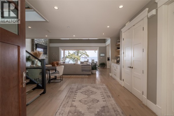 Entryway of a modern home with light wood floors, grey walls, and a distant ocean view. - 3089 Cook St, Chemainus