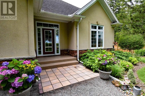 Entryway with stone steps, potted flowers, and large windows. - 3089 Niagara River Parkway, Fort Erie