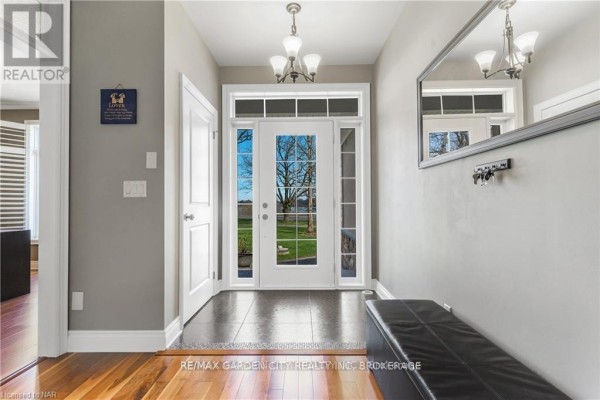 Interior foyer with hardwood flooring, coat hooks, and glass doors leading outside. - 3089 Niagara River Parkway, Fort Erie