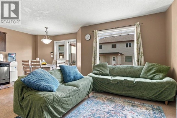 Living and dining area with beige walls, two couches, and a dining table. - 309, 10150 121 Avenue, Grande Prairie