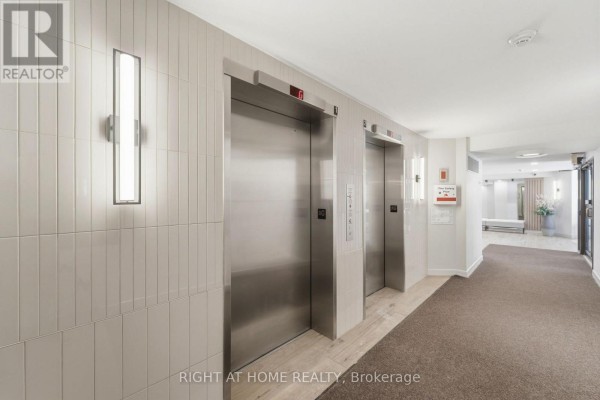 Building hallway with two brushed metal elevators, tiled walls, and carpeted floor. - 309 - 225 Alvin Road N, Ottawa
