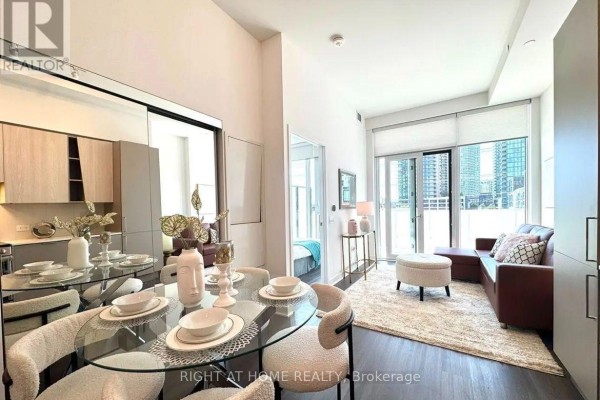 Apartment living and dining area with a glass table, brown sofa, and large window. - 309 - 3900 Confederation Parkway, Mississauga