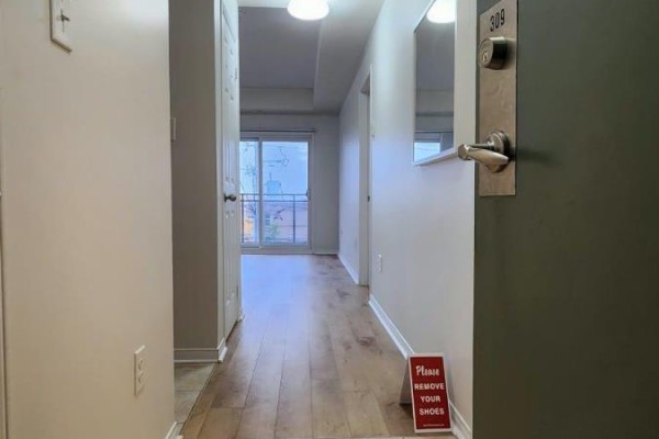 View from inside the apartment entrance looking down a hallway towards a balcony door. - 309 - 5150 Winston Churchill Boulevard, Mississauga