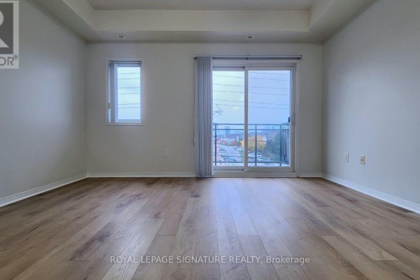 Empty living room with light wood flooring, white walls, and a sliding glass door. - 309 - 5150 Winston Churchill Boulevard, Mississauga