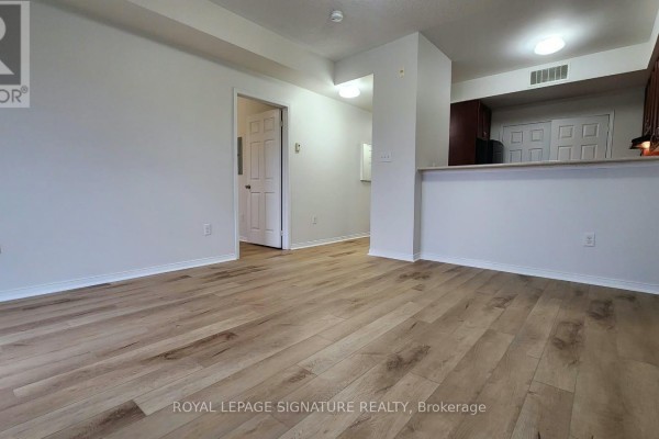 View of the living area and hallway, showing light wood floors and a partial view of the kitchen. - 309 - 5150 Winston Churchill Boulevard, Mississauga