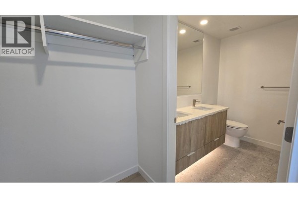 Bathroom with a double vanity, modern fixtures, and a toilet; walk-in closet on the left. - 309 1616  Lloyd Avenue, North Vancouver