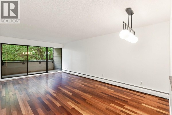 Empty living area with hardwood floors and large sliding glass doors opening to balcony. - 309 1710 W 13th Avenue, Vancouver