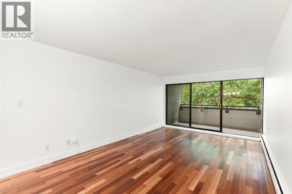Empty living space with hardwood floors and large window overlooking trees. - 309 1710 W 13th Avenue, Vancouver