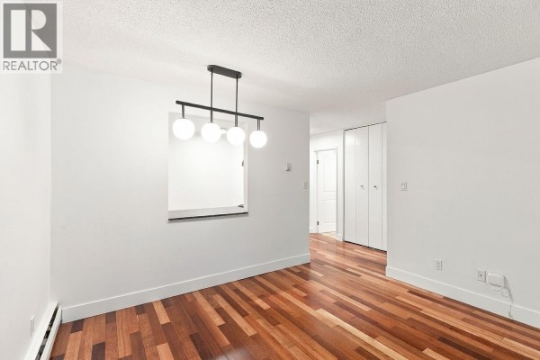 Dining area with pendant light, pass-through window to kitchen, and double closet doors. - 309 1710 W 13th Avenue, Vancouver