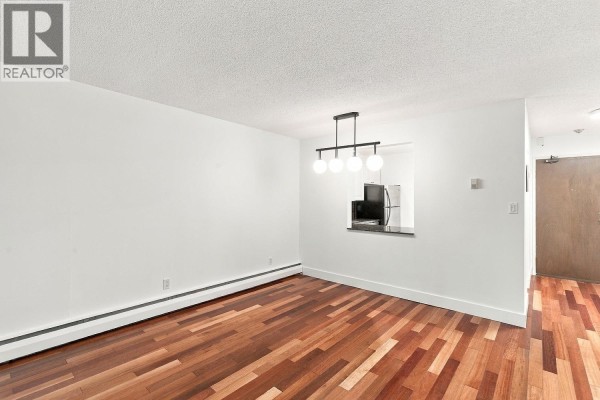 Dining area with pendant light and pass-through window revealing refrigerator and microwave. - 309 1710 W 13th Avenue, Vancouver