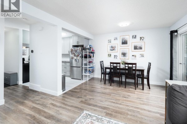 Dining area with a dark wood table and chairs, adjacent to the kitchen. - 309 2550 S Ospika Boulevard, Prince George