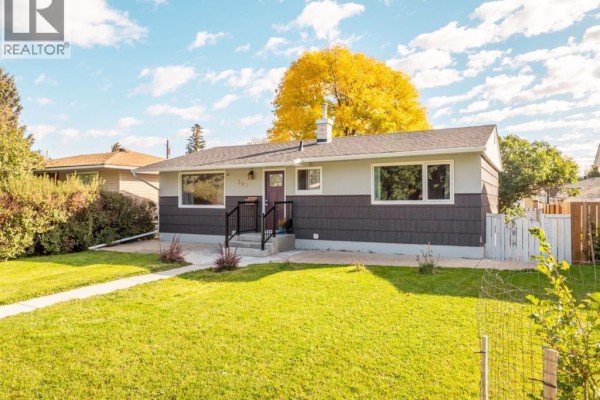 View of the front of a single-story home with light grey and dark grey siding, a walkway, and green grass. - 309 26 Street S, Lethbridge