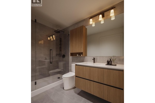 Bathroom with a walk-in shower, vanity with wood cabinets, and a modern toilet. - 309 4488 Hastings Street, Burnaby