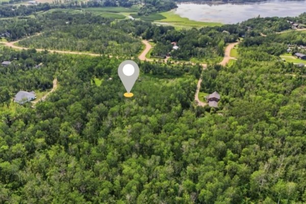 Aerial perspective of a vacant, wooded lot with a location marker and neighboring homes visible. - 309 East Lakeshore Road, St Malo