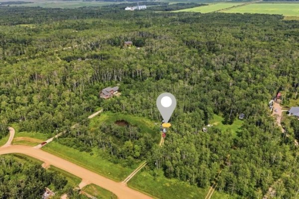 Drone shot of a large, treed property with a pond and outbuildings, showing proximity to roads and other houses. - 309 East Lakeshore Road, St Malo