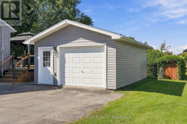A detached grey garage with a white overhead door and a side entrance door. - 309 George Street East, North Grenville