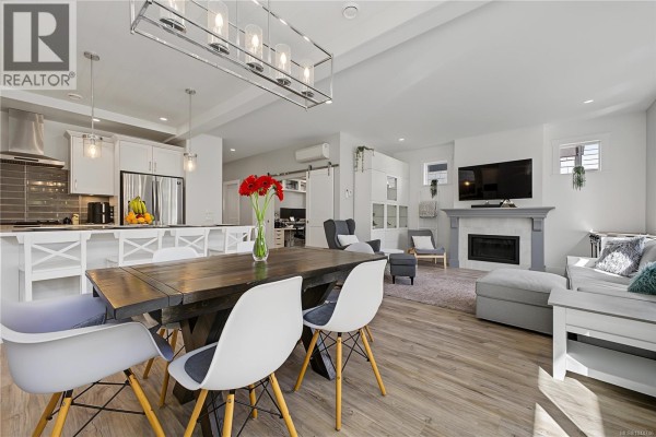 Bright white kitchen with a large island, stainless steel appliances, and a view of an office space. - 309 Seafield Rd, Colwood