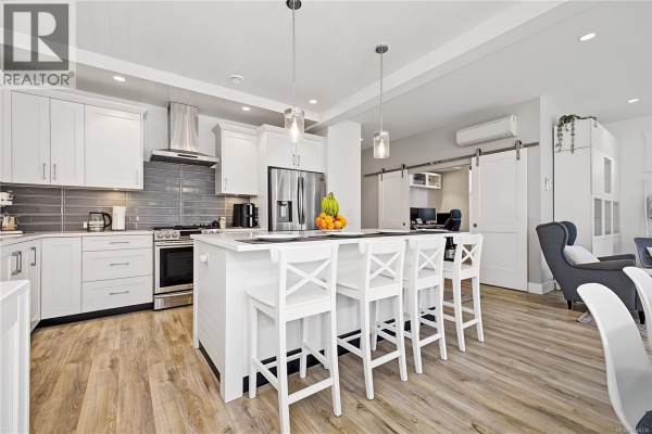 Open concept living and dining area with a wooden dining table, fireplace, and a grey sectional sofa. - 309 Seafield Rd, Colwood