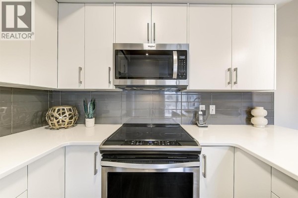 Kitchen with white counters and cabinets, stainless steel appliances, and island. - 3090 Burtch Road Unit# 201, Kelowna