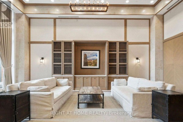Lobby lounge area with two white sofas, a wood coffee table, and built-in shelving. - 905 - 3091 Dufferin Street, Toronto