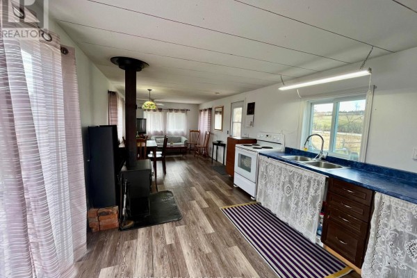 Combined kitchen and living area with a wood stove, dining table, sofa, and television. - 3092 Scotch Bush Road, Bonnechere Valley