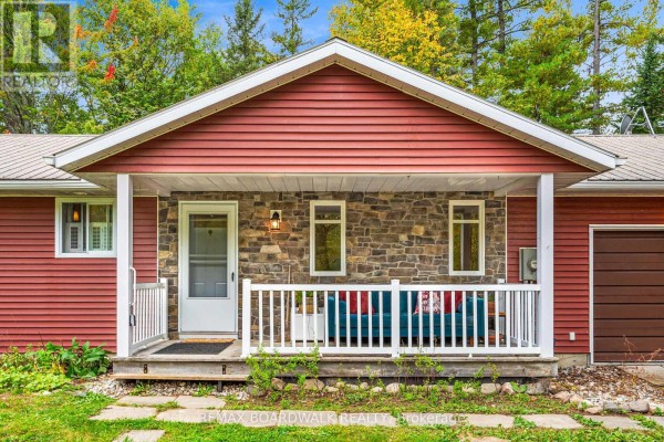 Front porch of a red siding house with stone accents and white railing. - 3099 8th Concession North Road, Mississippi Mills