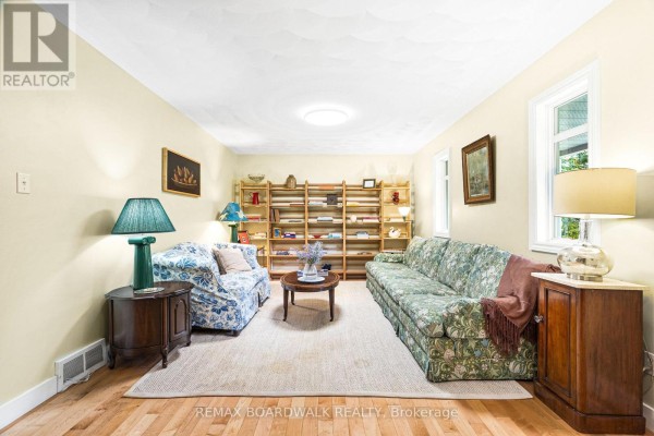 Living room with light yellow walls, sofas, shelves, and wood flooring. - 3099 8th Concession North Road, Mississippi Mills