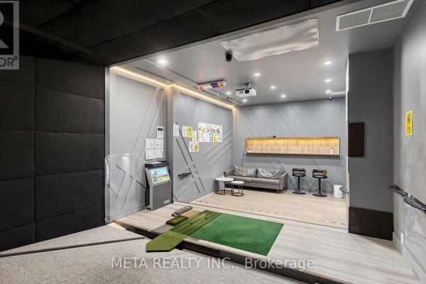 Indoor golf simulator room with seating area, projection screen, and golf mats. - 31 - 1600 Steeles Avenue W, Vaughan