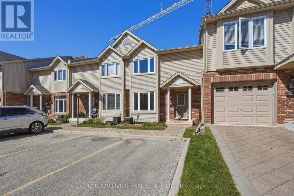 Exterior view of a beige townhouse with red brick accents and a grey garage door. - 31 - 1625 Purser Street, London East