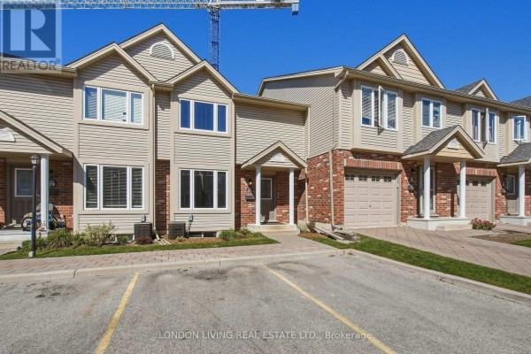 Exterior view of a beige townhouse with red brick accents and a grey garage door. - 31 - 1625 Purser Street, London East