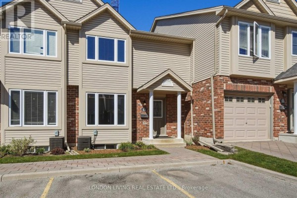 Exterior view of a beige townhouse with red brick accents and a grey garage door. - 31 - 1625 Purser Street, London East