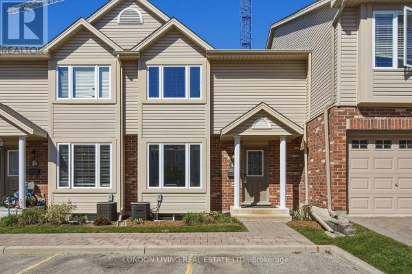 Exterior view of a beige townhouse with red brick accents and a grey garage door. - 31 - 1625 Purser Street, London East